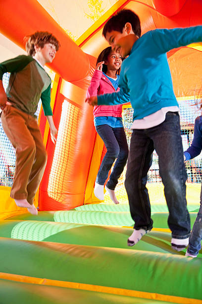 Multi-ethnic group of children (ages 7 to 10 years) jumping in inflatable bouncy castle.  Focus on African American girl (10 years).